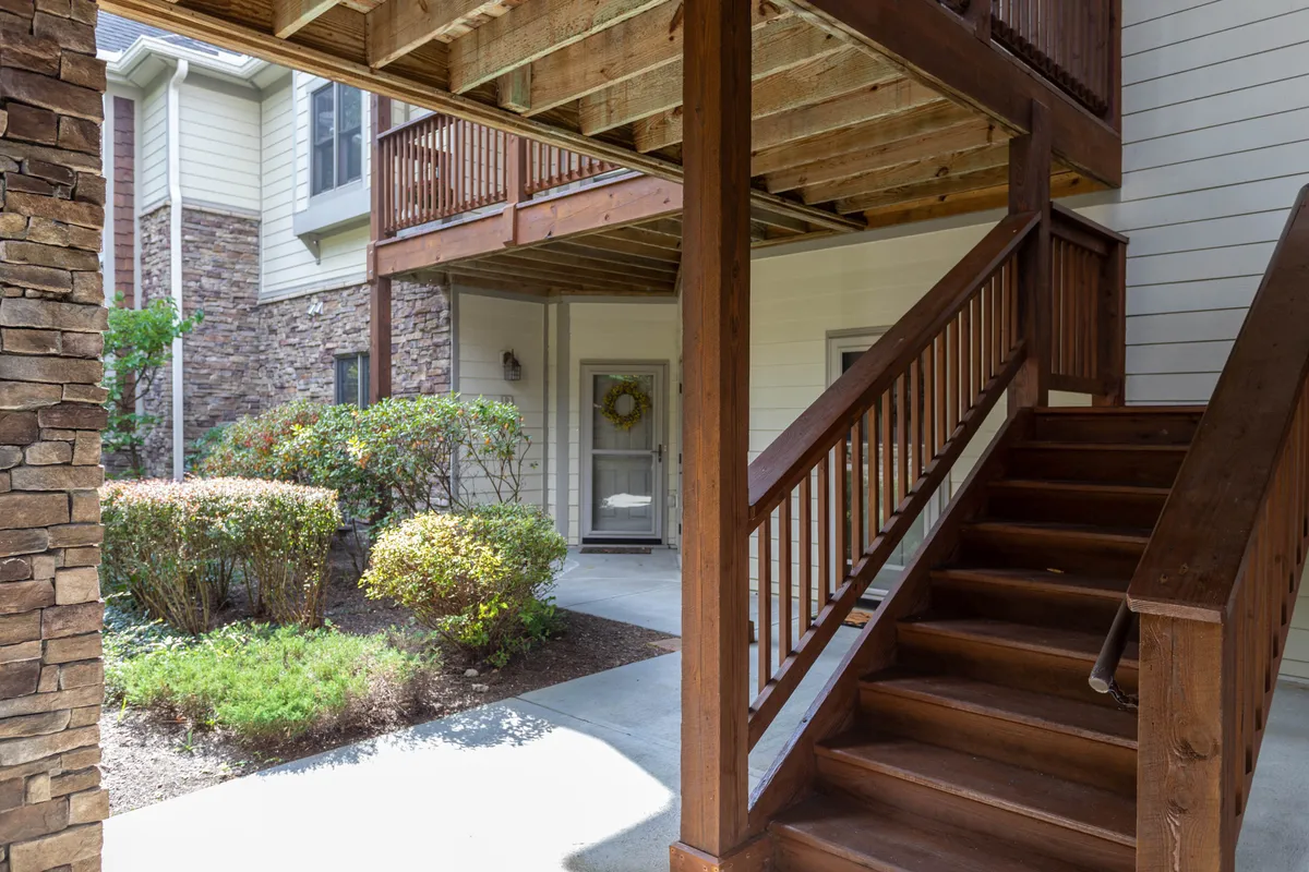 This image shows a welcoming entryway featuring a wooden staircase, stone columns, and a decorative wreath on the door. The space feels inviting and organized, suggesting ease of access and a well-maintained environment.
